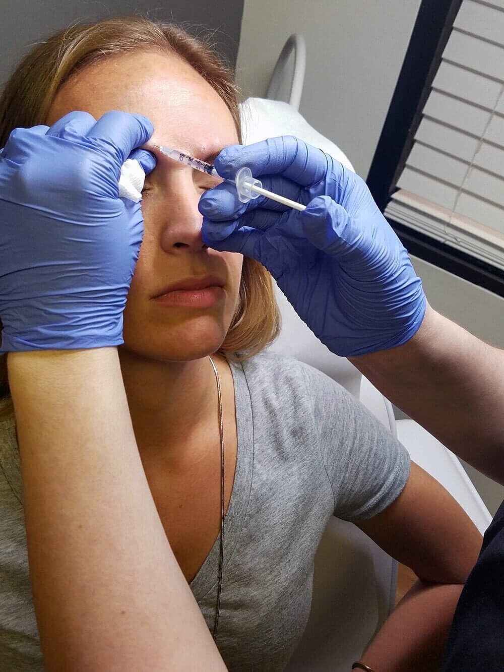Woman receiving cosmetic injection treatment in clinic.