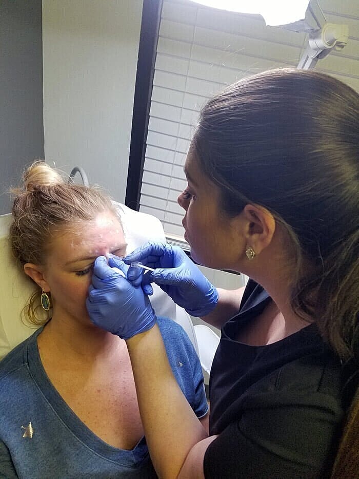 Woman receiving aesthetic treatment in clinic setting.