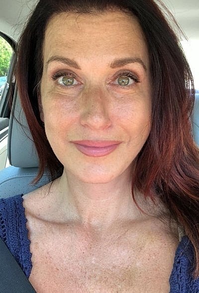 Woman with long hair smiling in car.