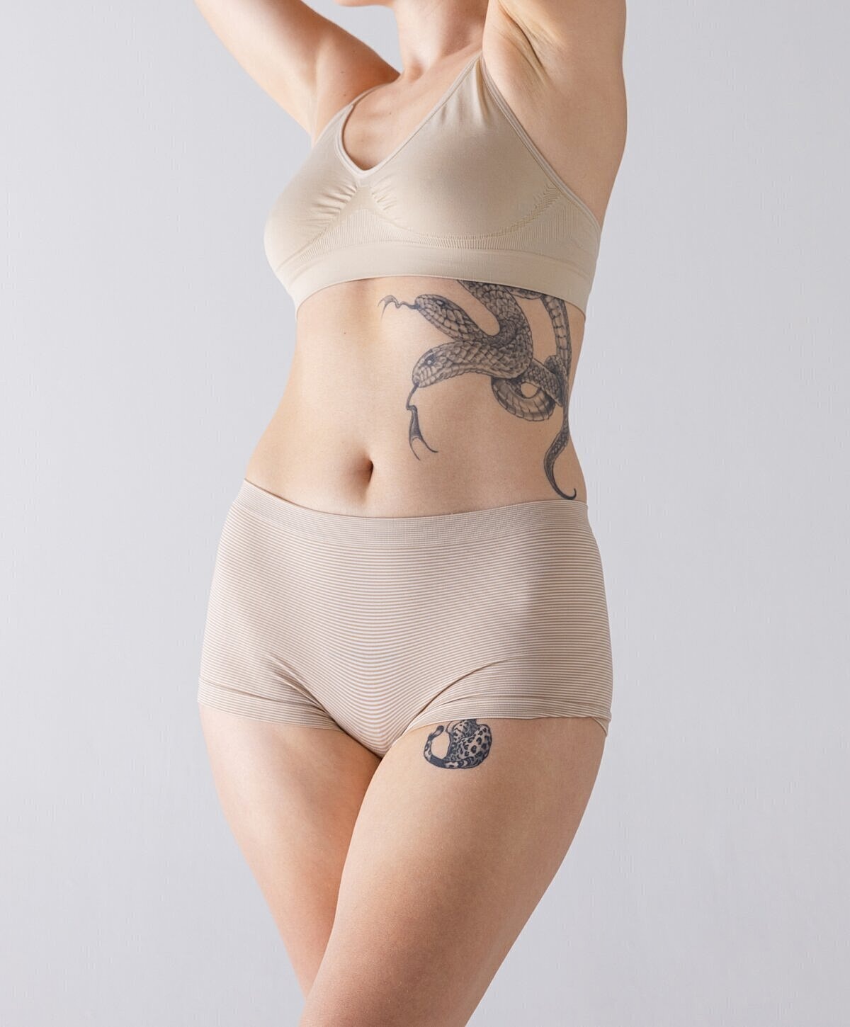Model in beige underwear with tattoos.