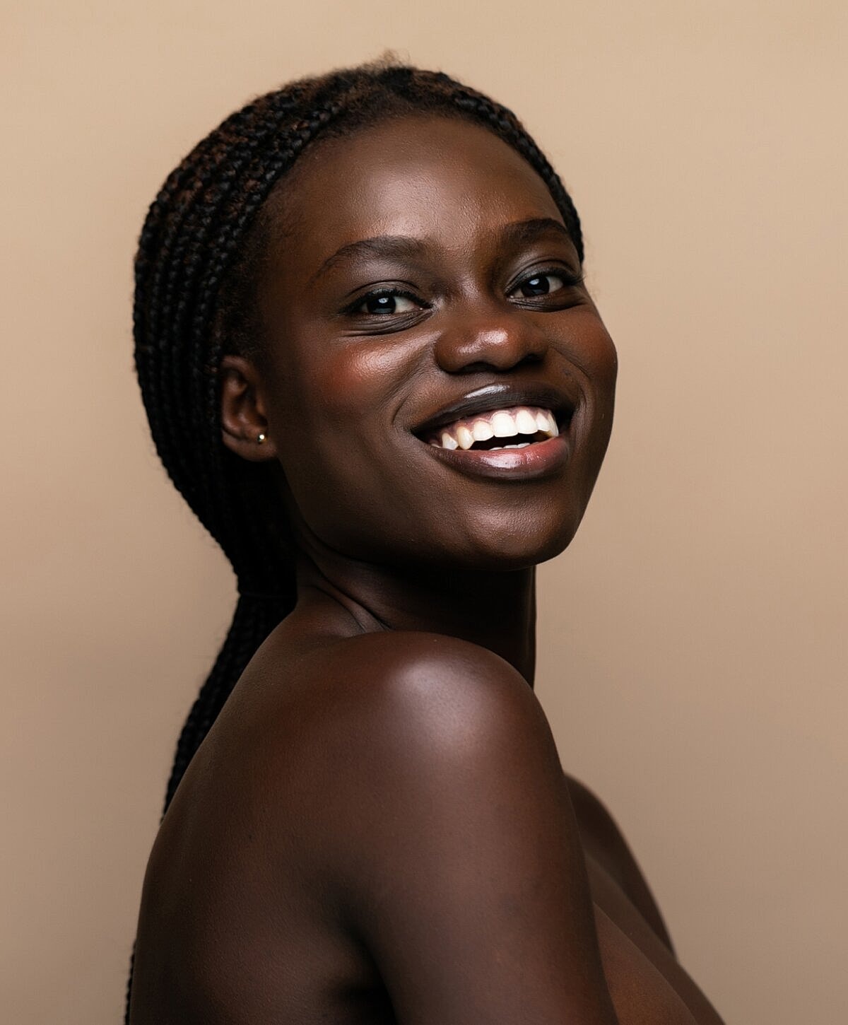 Smiling woman with dark skin and braided hair.