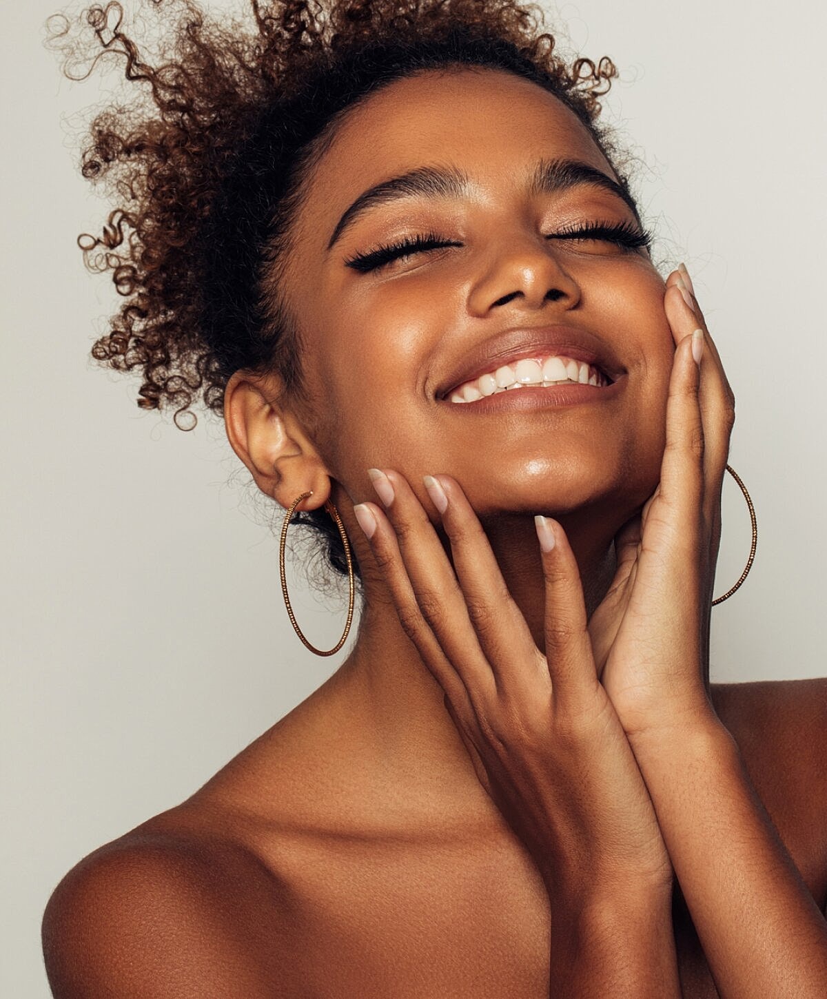 Smiling woman with curly hair and hoop earrings.