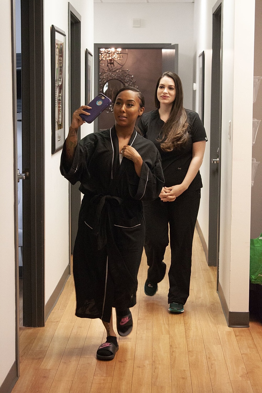 Two women in a hallway taking selfies.