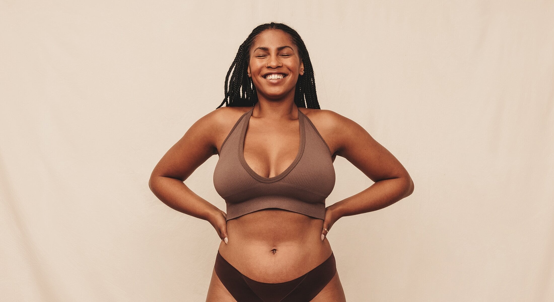 Smiling person in brown activewear against backdrop.