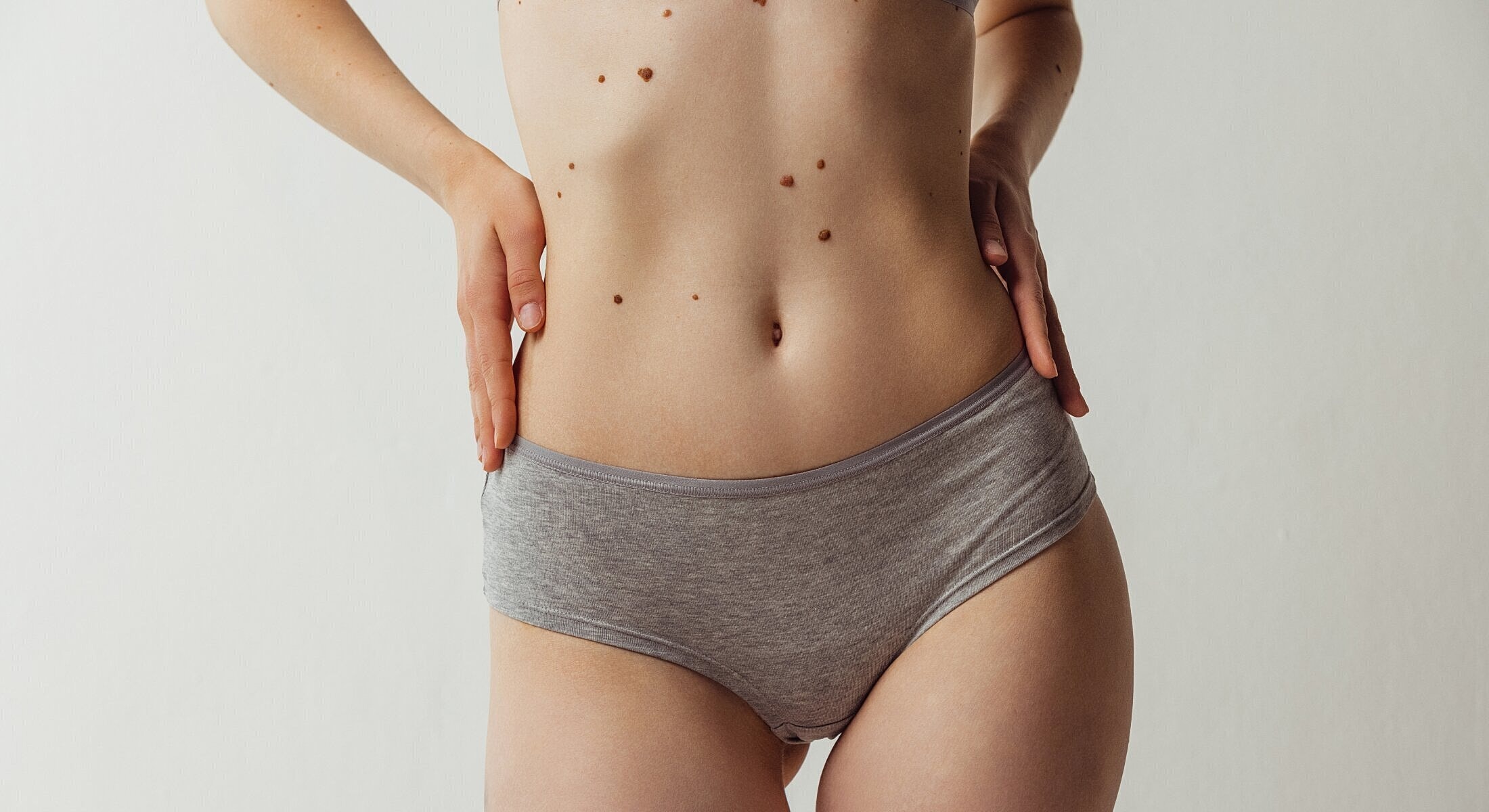 Female torso in gray underwear against plain background.