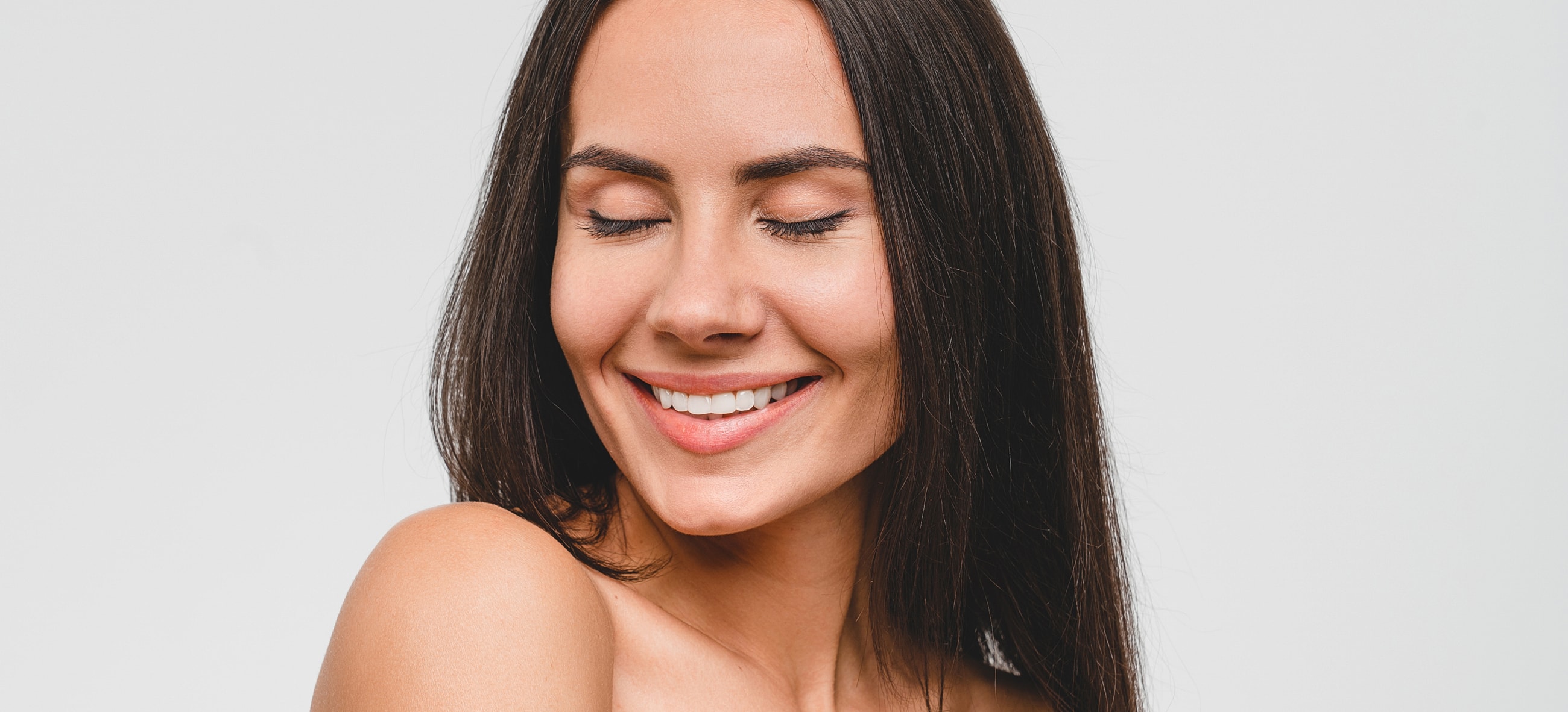 Smiling woman with long dark hair, studio background.