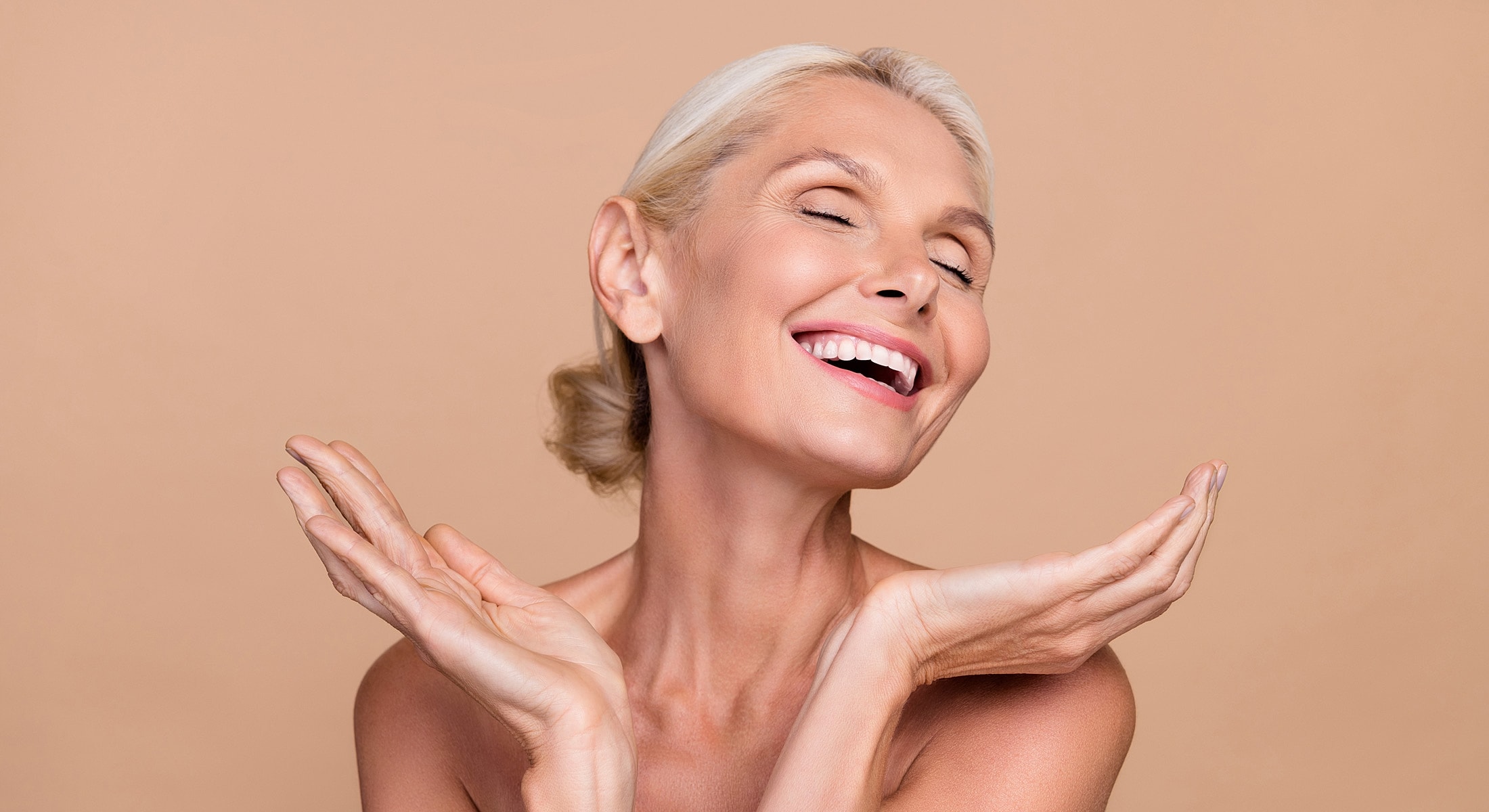 Smiling woman with joyful expression and hands raised.