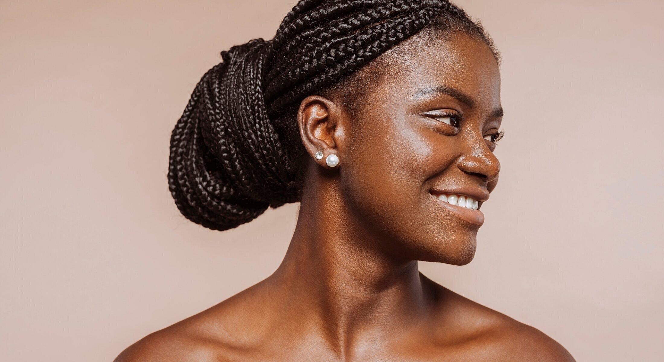 Woman with braided hair smiling against neutral background.